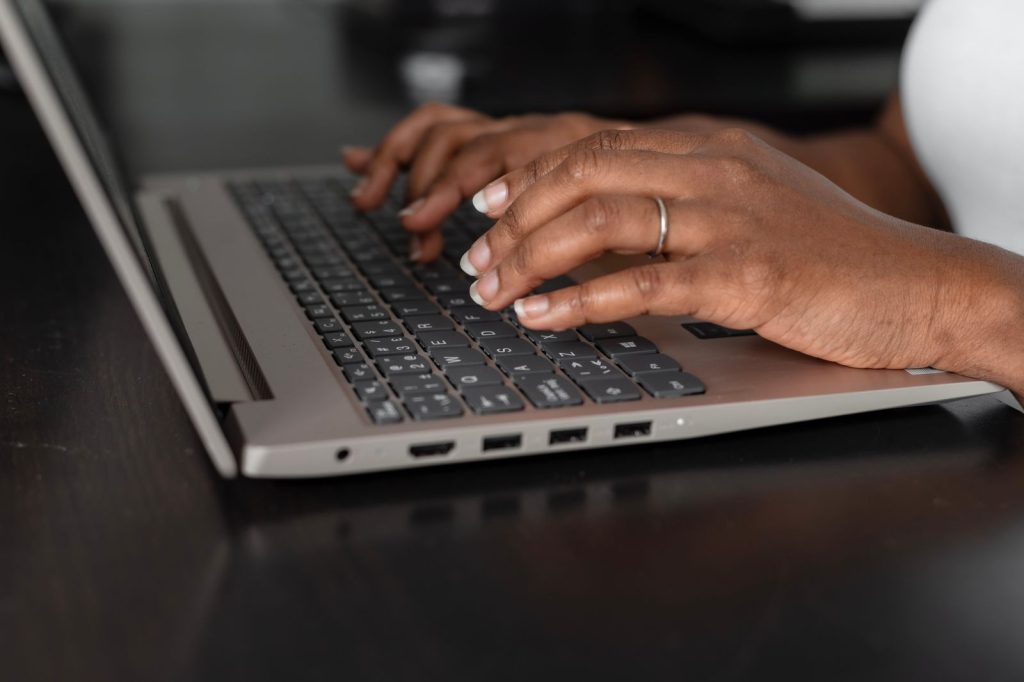 Close-up of hands typing on a laptop keyboard