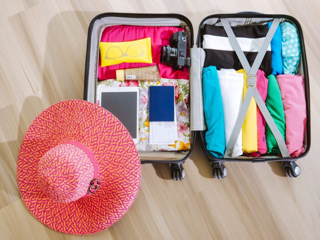 Packed open suitcase with a camera, a tablet, a passport, and folded clothes