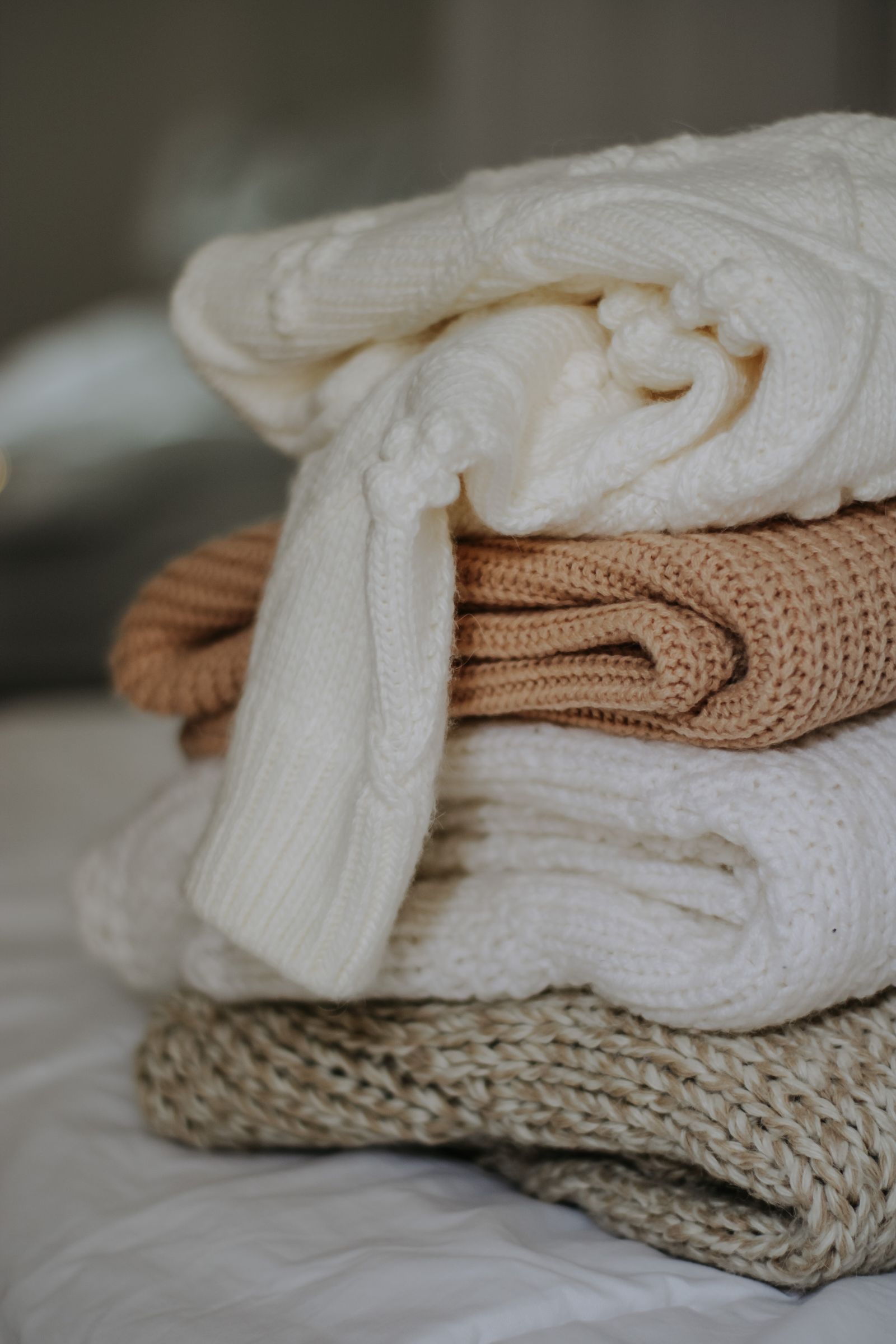 Stack of soft knitted sweaters in neutral colors