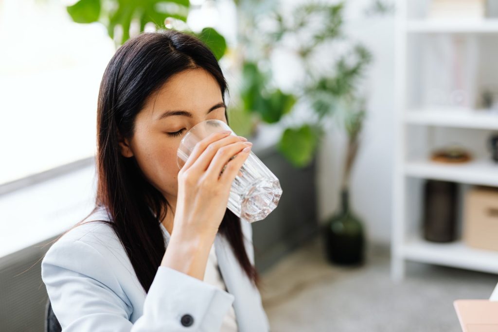 Woman drinking a glass of water at a desk