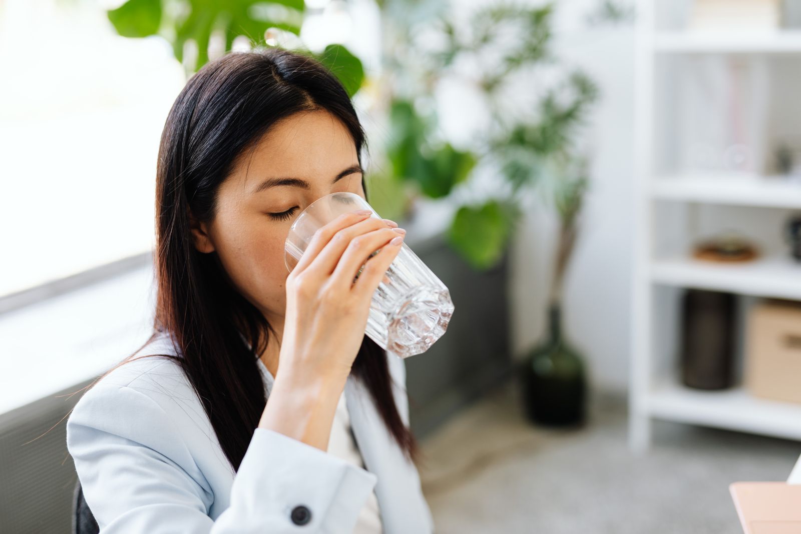Woman drinking a glass of water at a desk