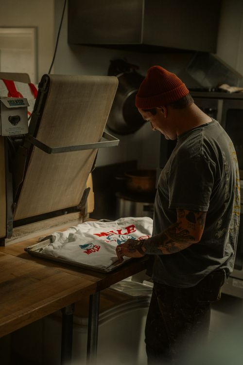 Man printing a custom t-shirt with a heat press in a workshop