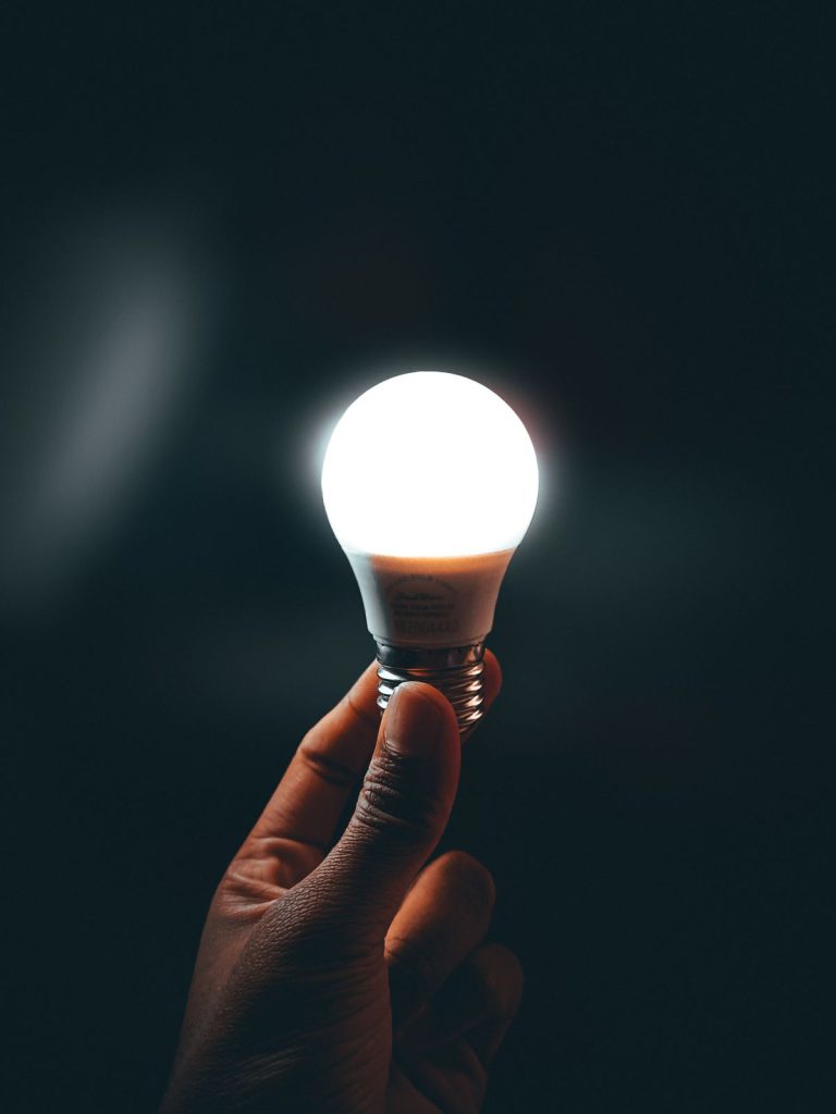 Hand holding a lit LED light bulb