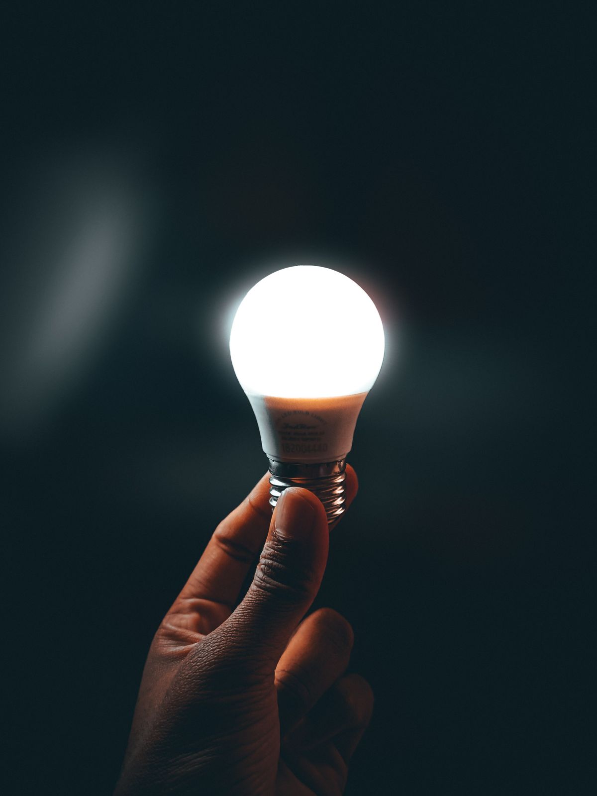 Hand holding a lit LED light bulb