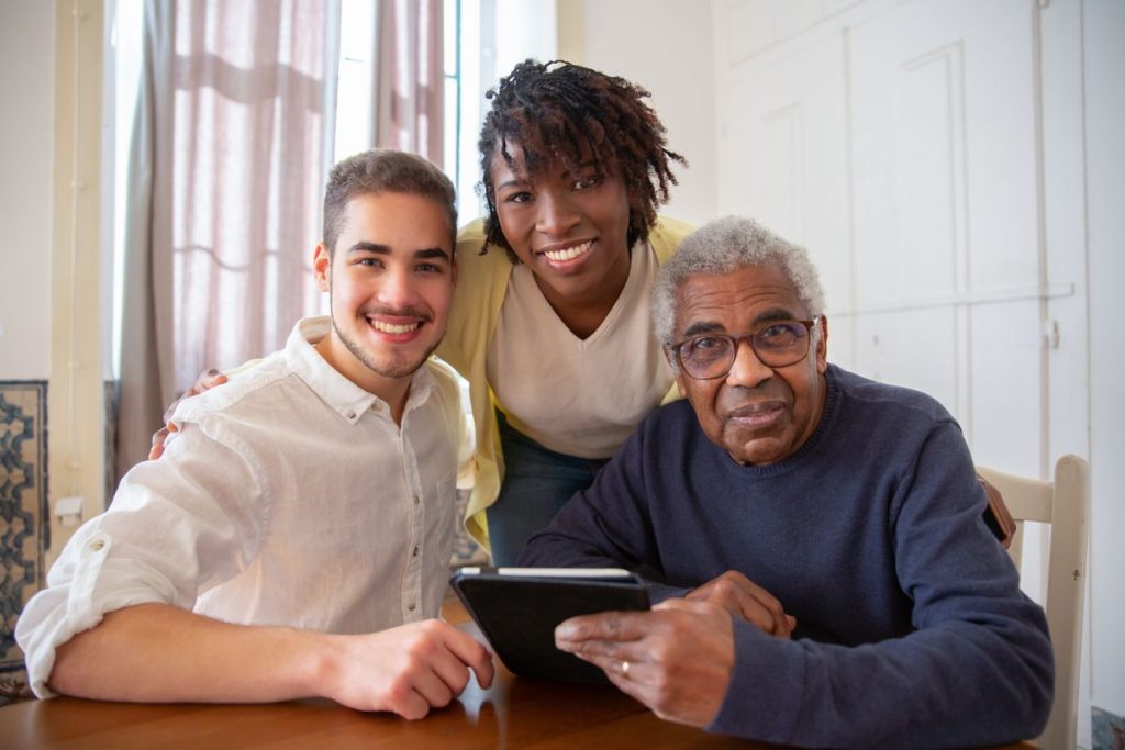 Older man using a tablet with help from younger family members