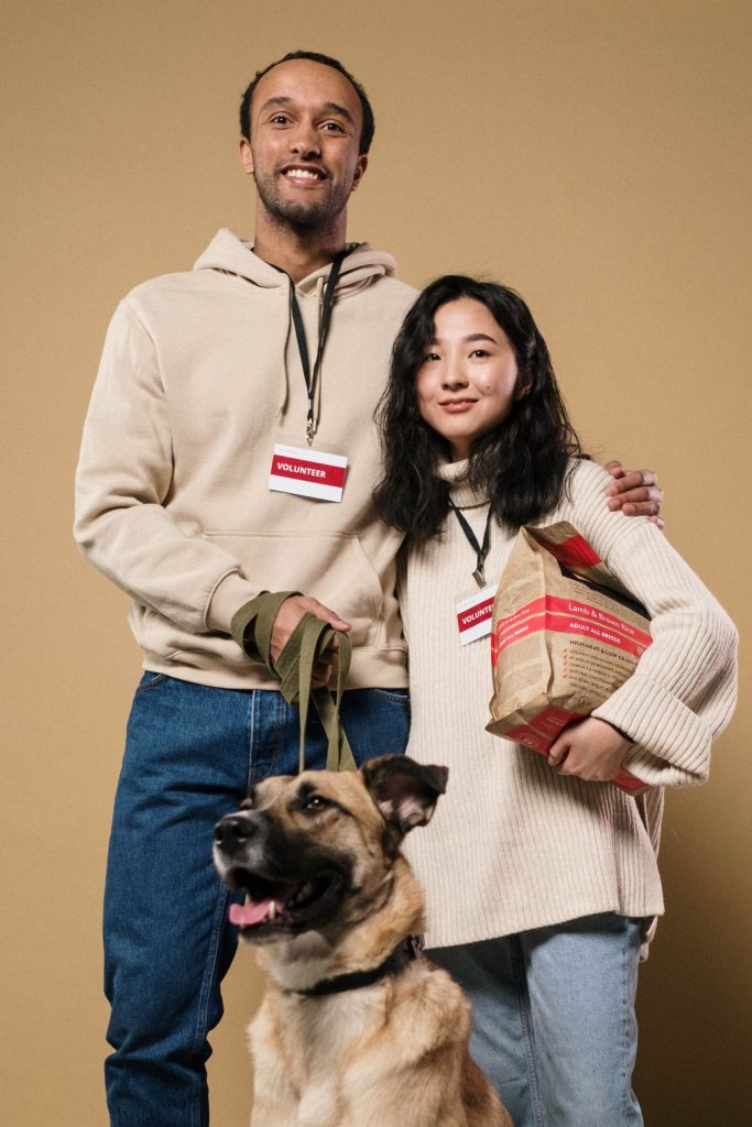 Two shelter volunteers with a dog and donated pet food